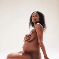 Black woman sitting naked in a studio feeling comfortable in her preg